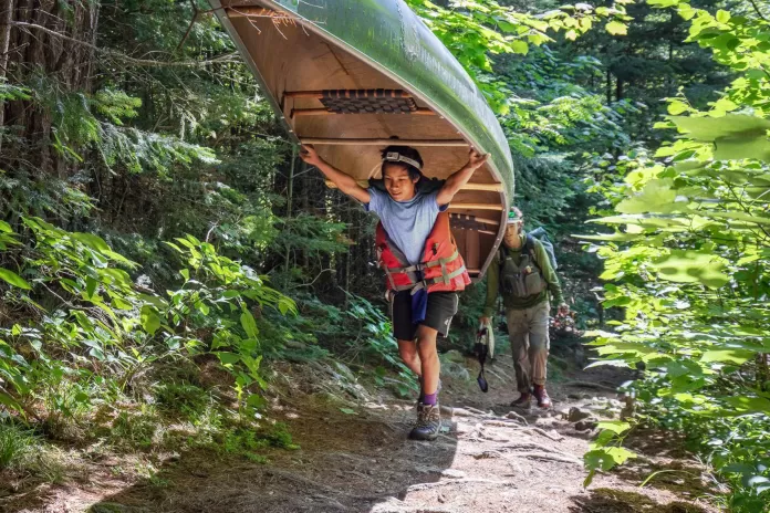 Two teens portaging a canoe