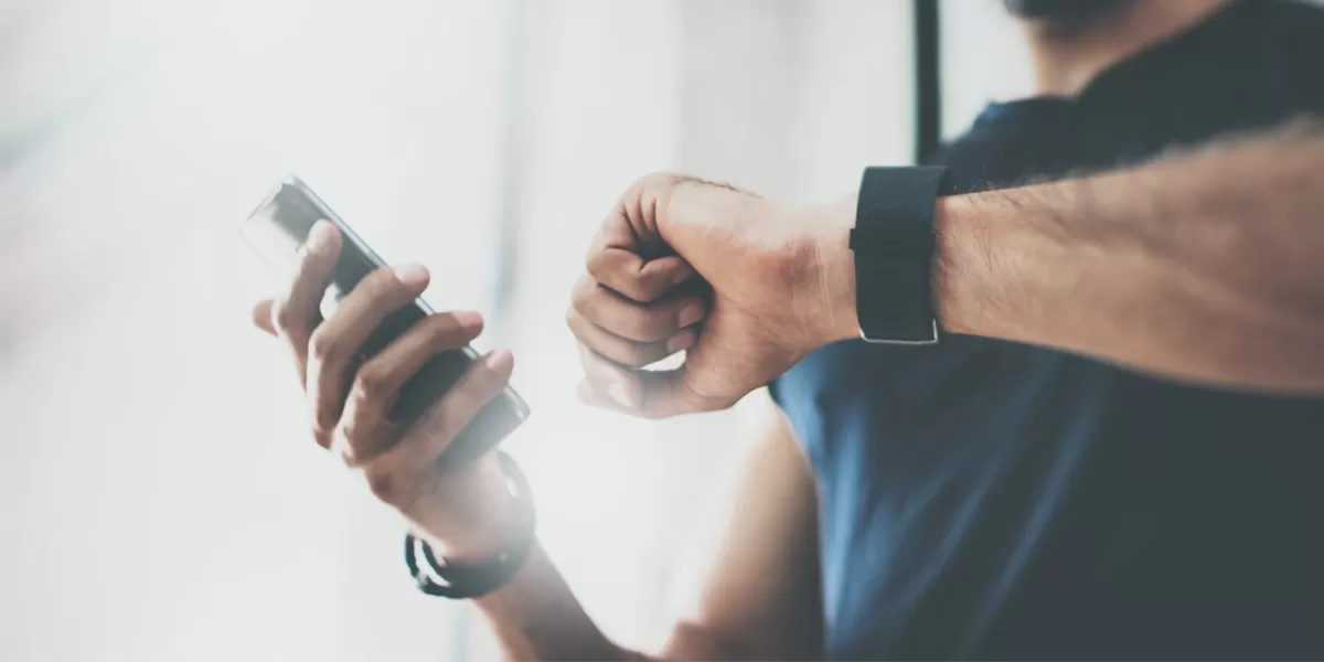 Caucasian man looks at fitness app on his Apple Watch and his iPhone Fitness App
