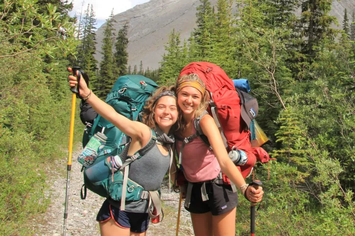 Two teenagers stop to pose on a hiking trail.