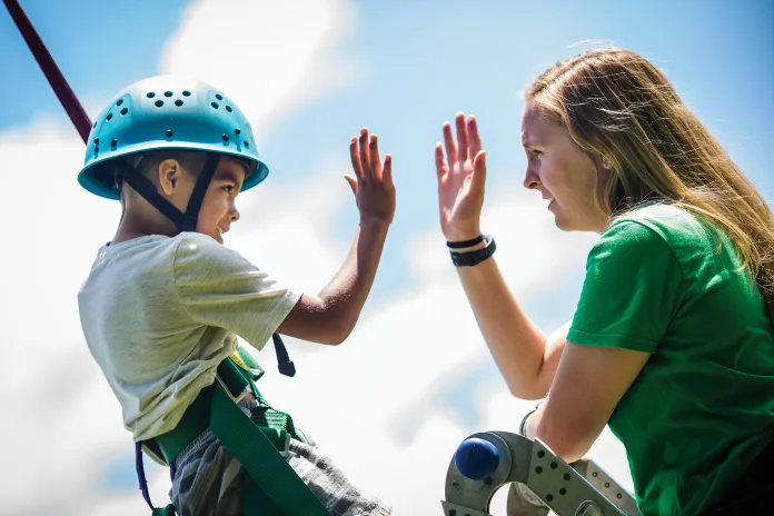 Boy giving camp counselor a "high five"