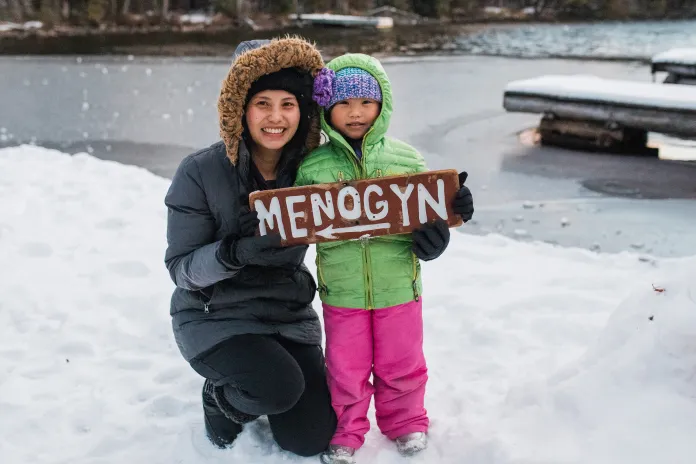 Mom and child holding a Menogyn sign in winter