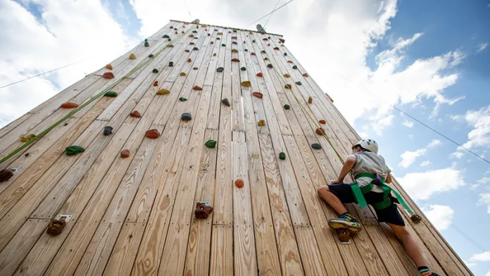 Boy scaling the Gathering Pines climbing wall.