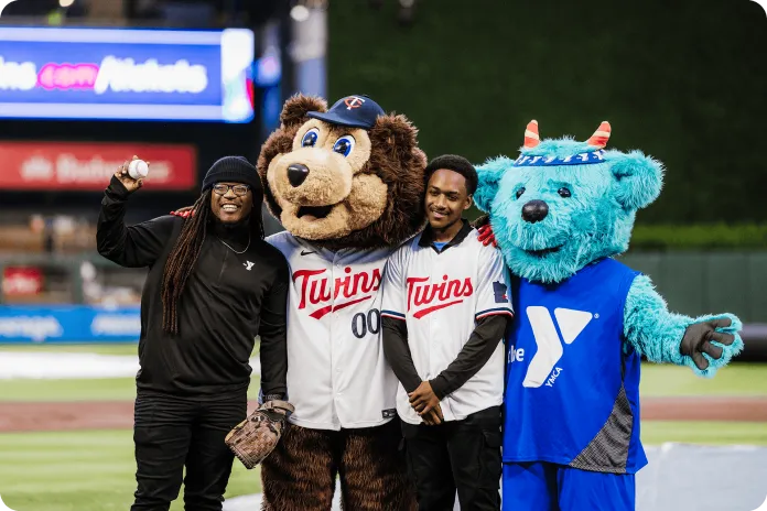D'Mario and his mentor poses with the Minnesota Twins mascot, T.C Bear, and YMCA of the North mascot, Sneakers, on the target baseball field.