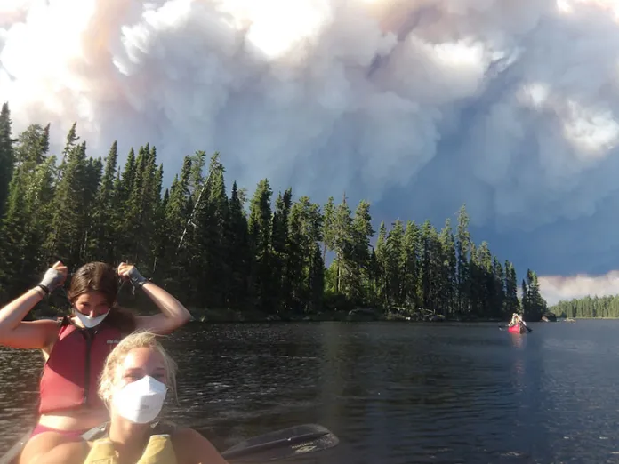 Nor’wester campers wearing masks with smoke in the background as they evacuate from their planned route