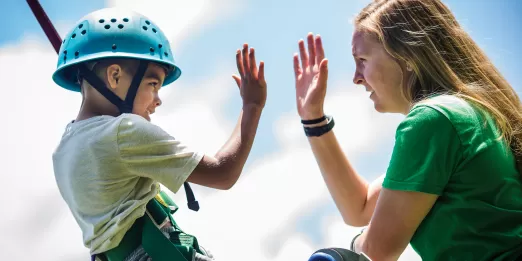 Boy giving camp counselor a "high five"